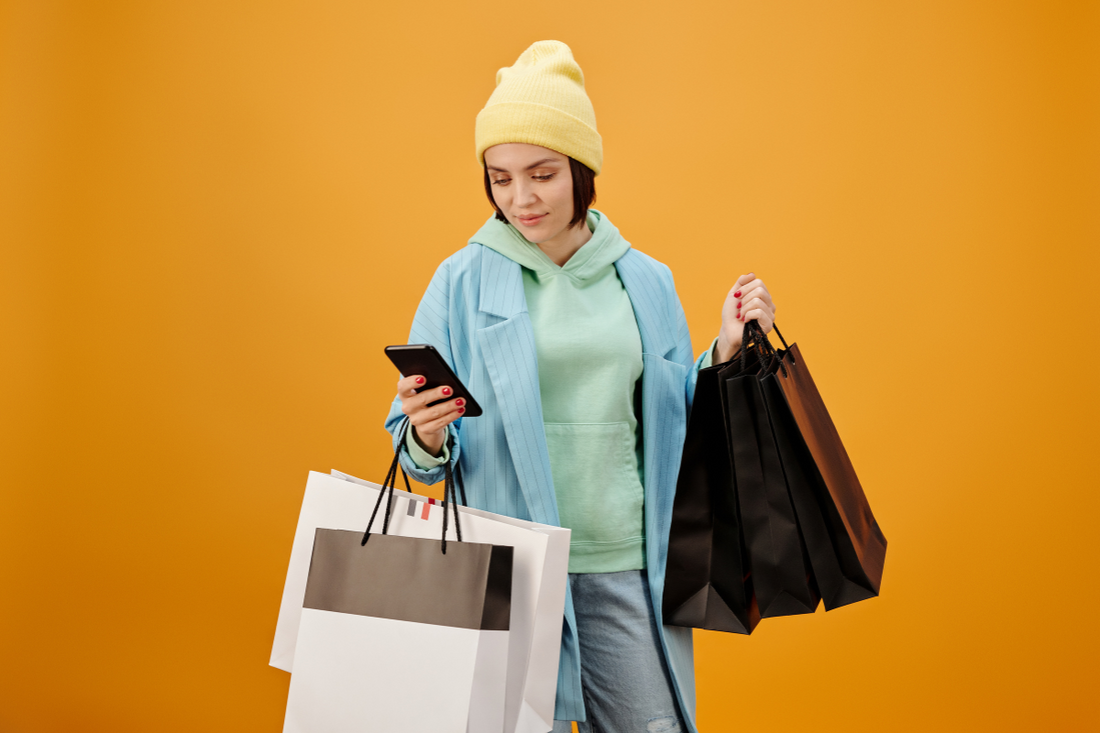 Online shopping experience for fashion, showcasing a variety of clothing options and a person browsing through a fashion website on a smartphone.